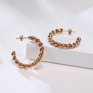 Détail des boucles d'oreilles créoles en forme de C torsadées en or rose poli
