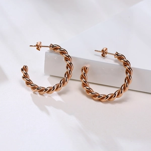 Boucles d'oreilles créoles torsadées minimalistes en or rose sur support blanc