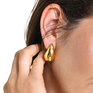 Close-up of polished gold teardrop earrings showing high-shine mirror finish on model