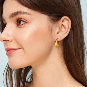 Gros plan d'un modèle portant des boucles d'oreilles dorées en forme de U poli