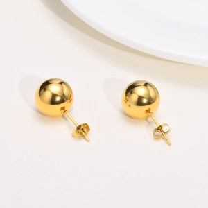 Gros plan de boucles d'oreilles boules dorées avec une finition miroir et des fermoirs papillon