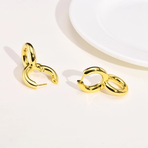 Detailed view of intertwined golden hoop earrings with high-polish mirror finish and clasp