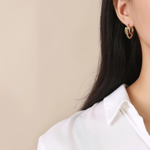 Boucles d'oreilles créoles doubles torsadées dorées en acier inox sur un mannequin
