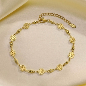 Detailed close-up of gold stainless steel layered anklet on luxury silk fabric background