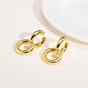 Close-up of polished gold double hoop earrings featuring a minimalist interlaced design