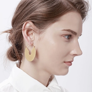 Boucles d'oreilles minimalistes en forme de U dorées portées par un mannequin de profil