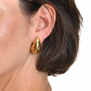 Close-up of polished gold teardrop earrings worn by a model for a modern minimalist look