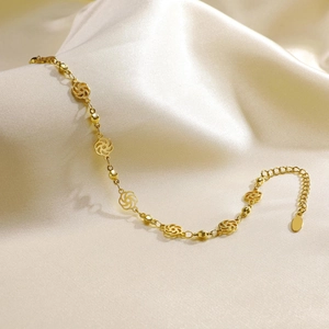 Detailed shot of a gold double-layer anklet with flower charms on champagne satin