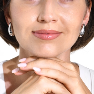 Polished silver teardrop hollow stud earrings in stainless steel on female model