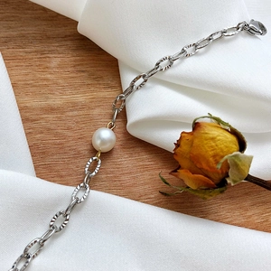 Detail of silver textured steel chain necklace featuring a glossy freshwater pearl
