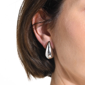 Macro shot of a silver teardrop earring on a model showing minimalist polished metal