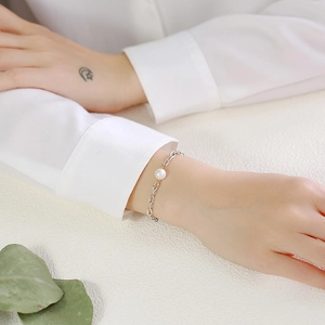 Detail of freshwater pearl on silver-tone stainless steel chain worn on a wrist