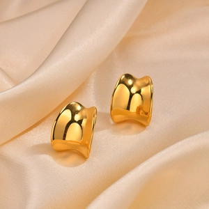 Macro shot of gold irregular C-shape earring on champagne satin fabric texture