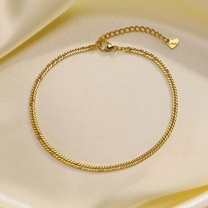 Detailed close-up of a gold stainless steel double-layered anklet on silk background