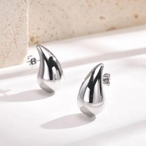 Macro shot of silver teardrop stud earrings with a high-polished mirror finish