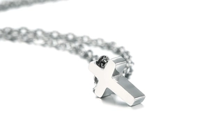 Macro shot of polished stainless steel cross pendant with mirror finish on thin chain