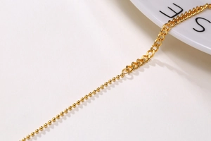 Macro detail of 18K gold plated mixed link chain with ball and curb textures