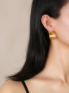 Close-up of a model wearing minimalist polished gold wide hoop earrings in stainless steel
