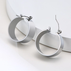 Close-up of thick silver stainless steel hoop earrings with polished metallic texture