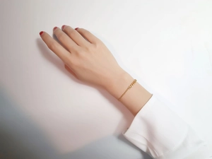 Detail of 18K gold stainless steel bead and link chain bracelet worn on wrist