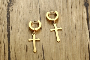Detailed view of 40mm golden stainless steel cross hoop earrings on a wood background