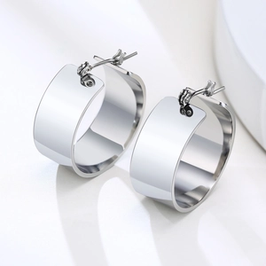 Detailed view of polished wide-band silver hoop earrings with a sleek mirror finish