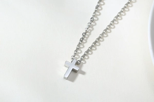 Detailed view of polished stainless steel cross pendant on an O-chain link necklace