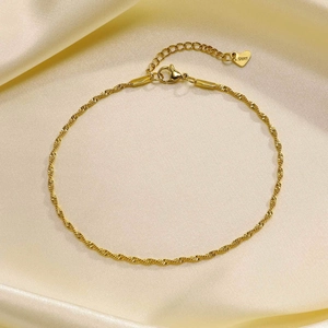 Detail of gold stainless steel twisted chain anklet with heart pendant on silk