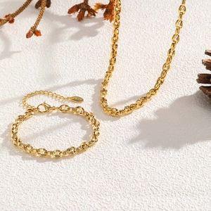 Dettaglio del set collana e bracciale dorati con incisione K18 su fondo strutturato