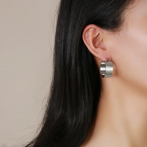 Minimalist wide silver hoop earring with matte finish worn by a model in a close-up