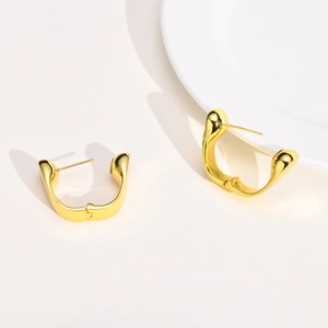 Macro detail of polished gold-finished U-shape geometric hoop earrings on minimalist background