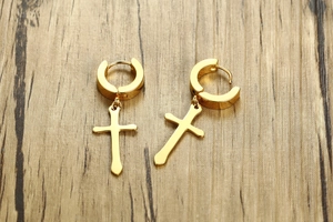 Detailed view of 40mm golden stainless steel cross pendant earrings on a wood background