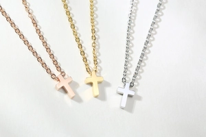 Three minimalist titanium steel cross necklaces in rose gold, gold, and silver finishes