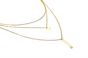 Gros plan détaillé du collier doré triple couche avec pendentifs disque et barre droite