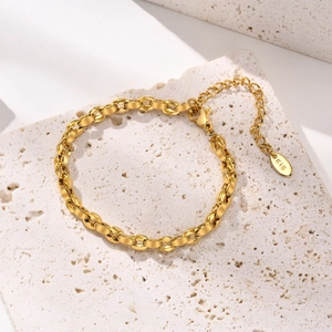 Dettaglio del bracciale a catena dorata con chiusura a moschettone e piastrina K18 su pietra