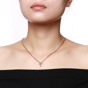 Close-up of a minimalist rose gold cross necklace on a model's neck with a sleek O-chain