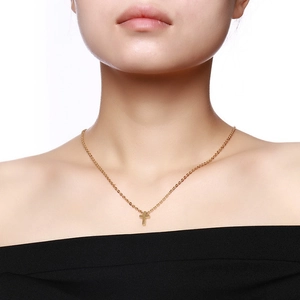 Close-up of minimalist gold cross necklace on model with polished stainless steel finish
