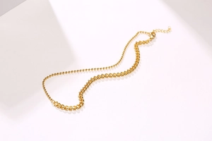 Detail of 18K gold double-layer necklace with ball and textured cuban chain link