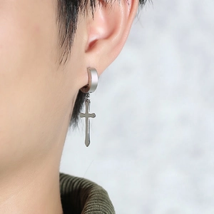 Macro view of polished silver stainless steel cross earring on male model ear