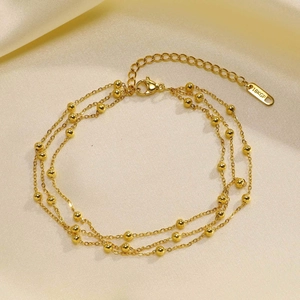 Detailed macro of gold-plated 18KGP three-layer bead anklet on silk texture background