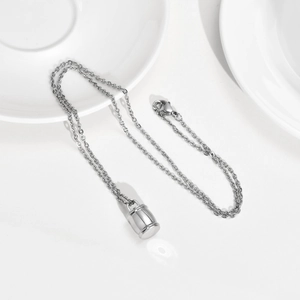 Détail du pendentif urne cylindrique poli en acier inoxydable sur une chaîne fine en O