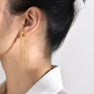 Close-up of golden stainless steel fringe earrings with geometric triangle design