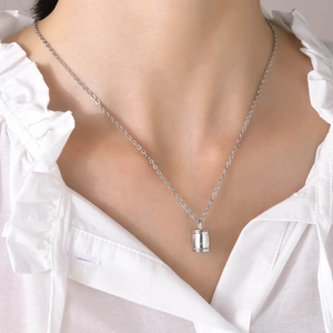 Vue rapprochée du collier urne cylindrique en acier poli sur le cou d'un mannequin