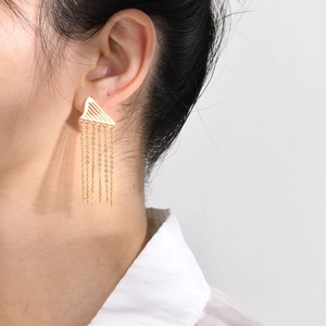 Close-up of a gold stainless steel tassel earring worn by a model with fringe details