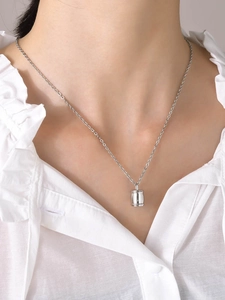 Collier à pendentif barillet en argent poli sur un mannequin en chemisier blanc