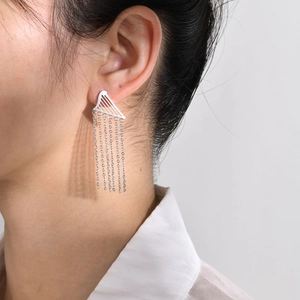 Detail of silver tassel earring with harp design worn by a model in profile view