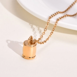Vue macro d'un pendentif urne cylindrique doré avec surface en acier inoxydable poli