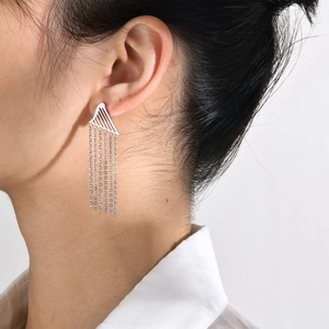 Close-up of silver steel tassel earrings with geometric triangle shape on ear
