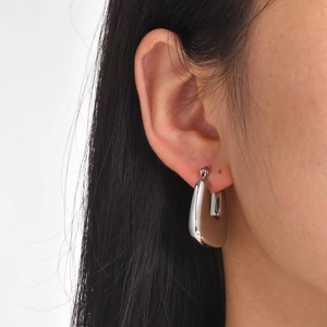 Gros plan de boucles d'oreilles en U évidées en argent poli portées par un mannequin chic