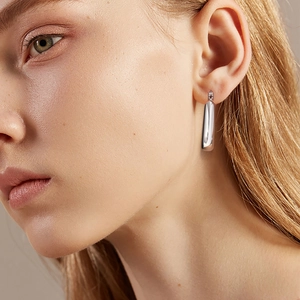 Détail macro de boucles d'oreilles polies en acier inoxydable en forme de U argenté